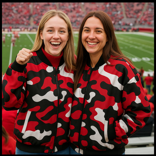 Two women wearing red, black, and white camouflage jackets at a sports event.