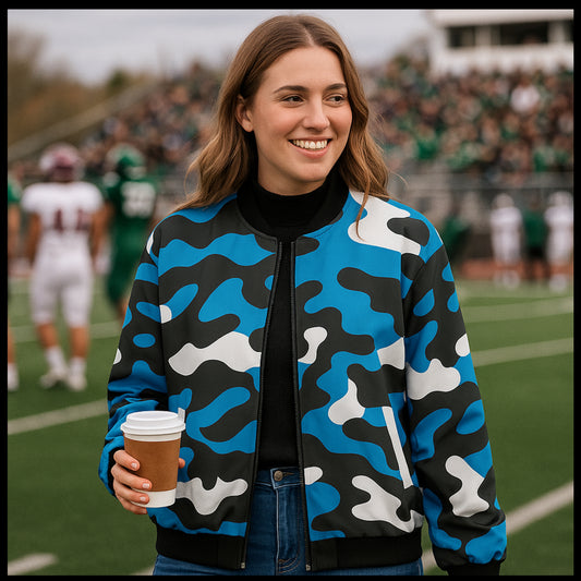 Person wearing a blue camouflage jacket holding a coffee cup on a sports field.