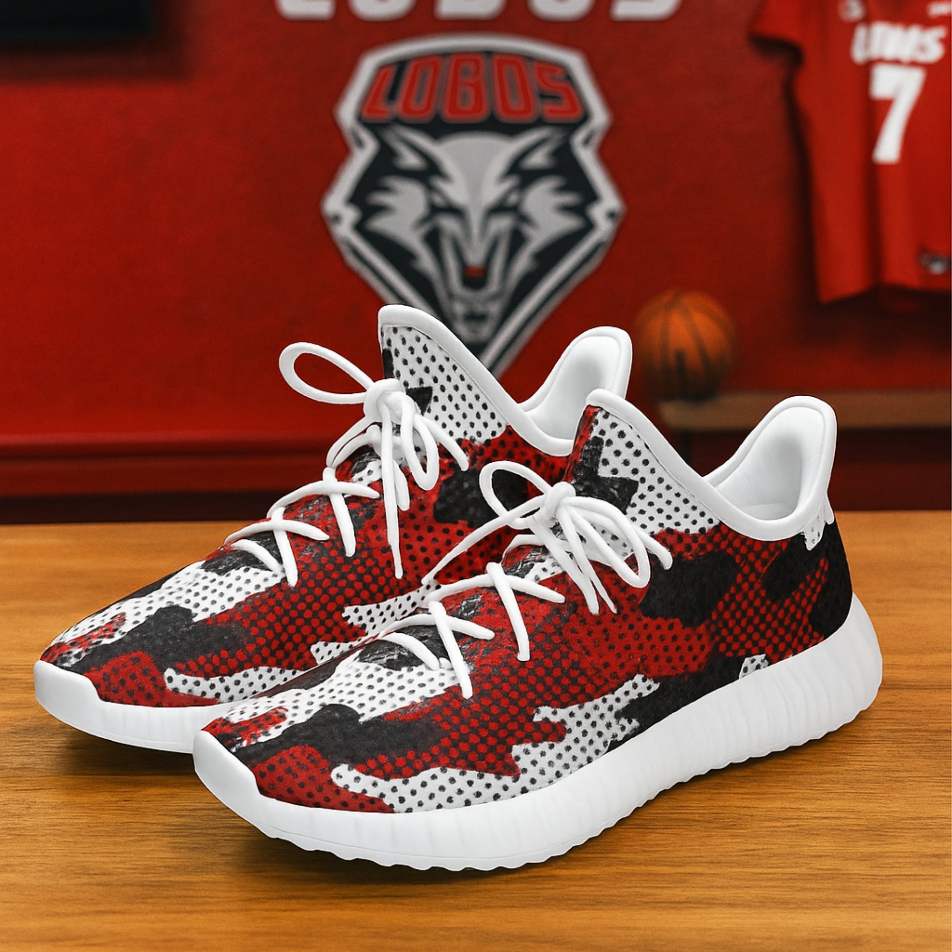 Red and black patterned sneakers with white laces on a wooden surface, with a blurred background featuring a logo and jersey.
