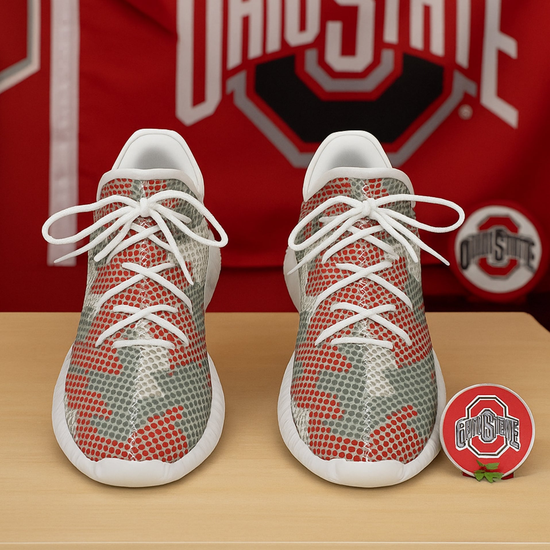 Red and gray patterned sneakers with white laces on a wooden surface, Ohio State logo in the background.