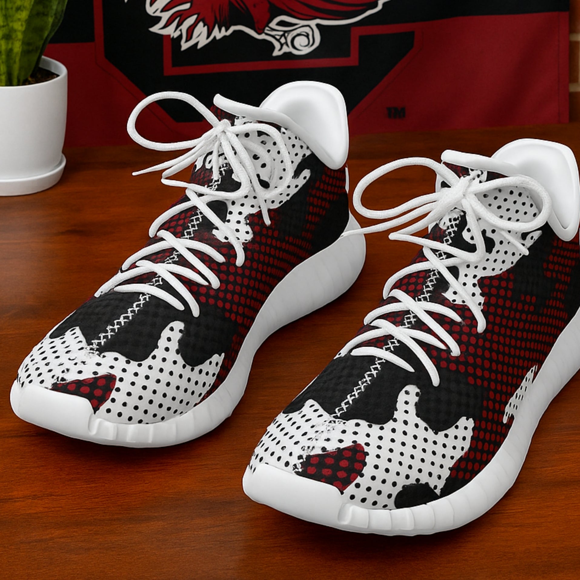 Pair of black, white, and red high-top sneakers on a wooden surface with a blurred background.