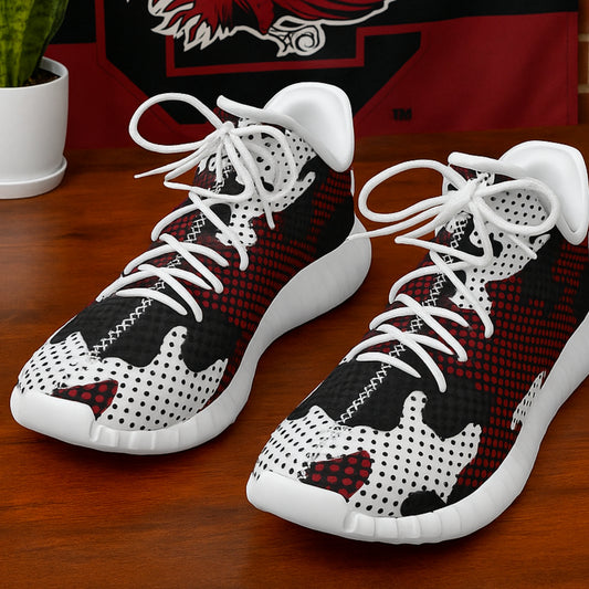 Pair of black, white, and red high-top sneakers on a wooden surface with a blurred background.